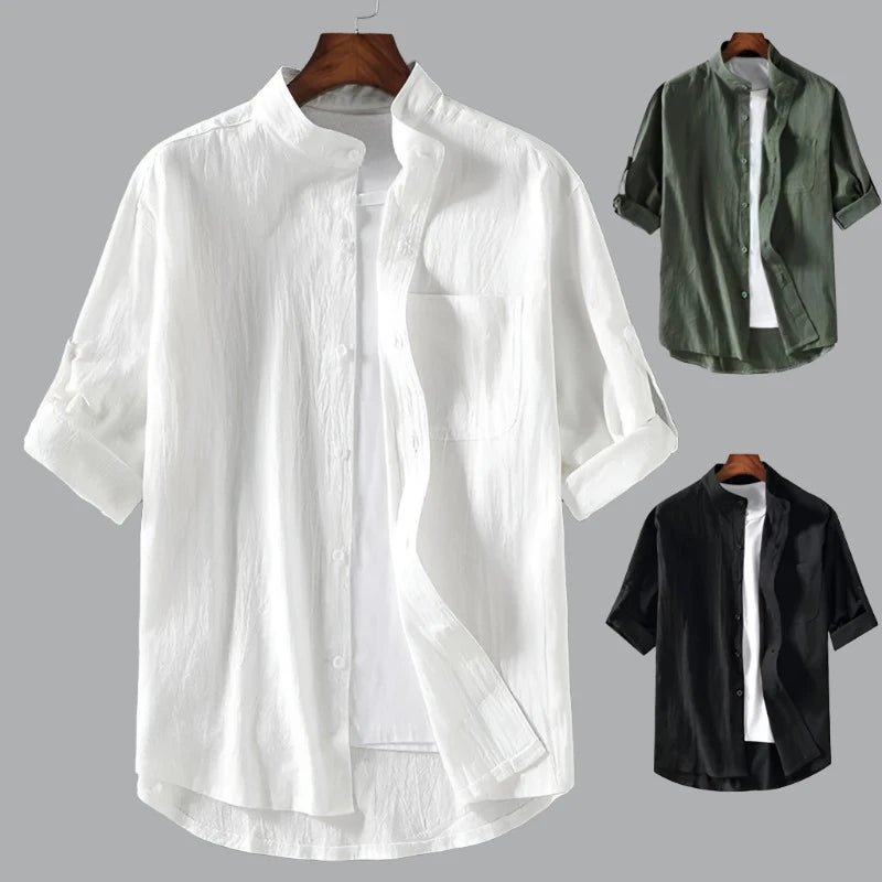 A white short sleeve shirt, along with a green one and a black one hanging on a hangar.